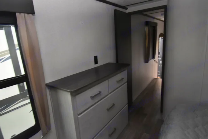 Explore this RV rental's cozy bedroom, with a dresser, window, and adjoining hallway. Perfect for travel comfort.. Other Montana High Country 2021