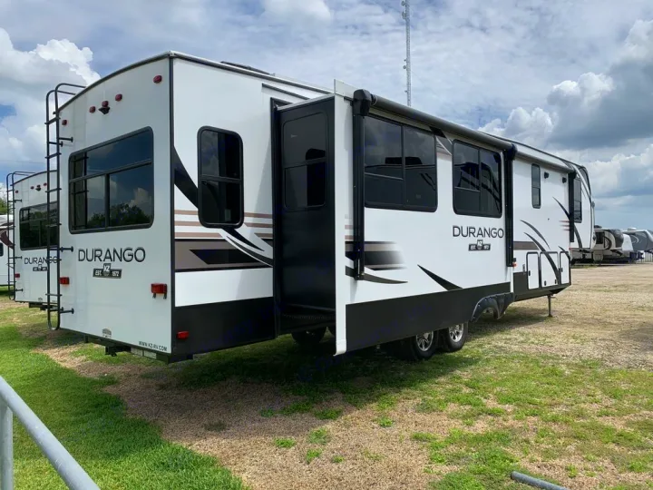 Side view of a large white and black Durango fifth-wheel RV with a slide-out extended, great for an RV rental adventure.. KZ Recreational Vehicles Durango 2021