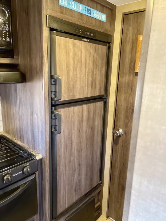 RV rental kitchen featuring a Dometic refrigerator, Suburban stove/oven, and microwave.. Pacific Coachworks Panther 2019