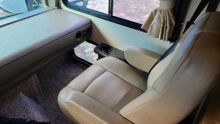 RV rental: Interior shot showing a tan captain's chair, dashboard, window view, and cup holder. Ready for your journey.. Fleetwood Flair 2017