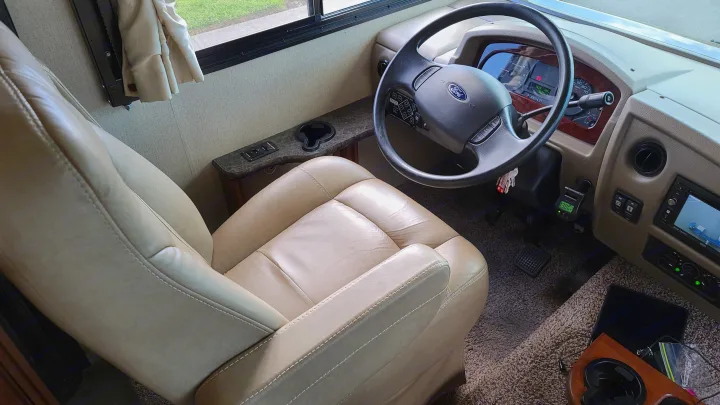 RV rental: View of the spacious driver's area with a beige leather seat, Ford steering wheel, and dashboard.. Fleetwood Flair 2017