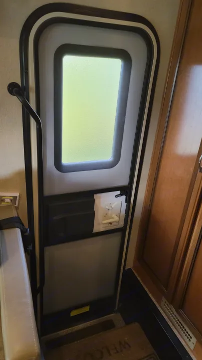 RV rental interior: Large, rounded-corner window with privacy glass and crank, wooden cabinets, and seating.. Fleetwood Flair 2017