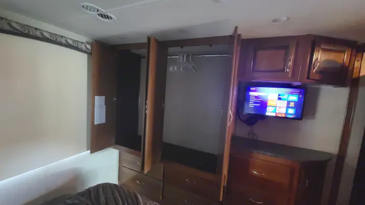 This RV rental offers storage: a wardrobe with hangers, dresser, and a mounted TV in the bedroom area.. Fleetwood Flair 2017