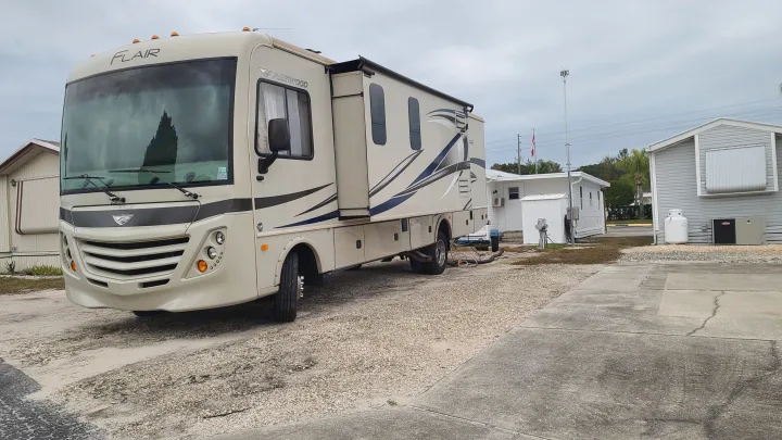 Explore this spacious Class A motorhome, perfect for **rv rental**, parked on a gravel lot near modular homes under a cloudy sky.. Fleetwood Flair 2017