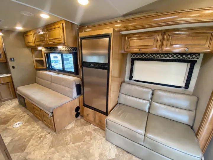 Explore a well-equipped RV rental interior featuring a modern fridge, ample cabinets, and two distinct seating zones for comfort.. Thor Motor Coach Siesta 2017