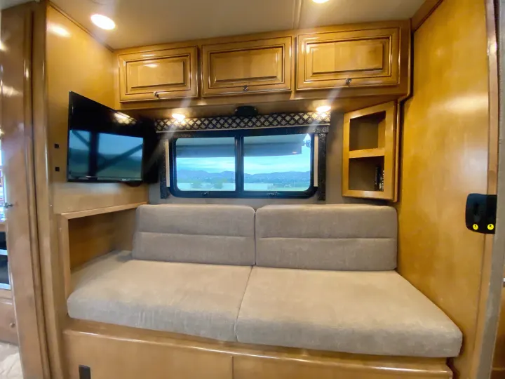 RV rental interior: light wood cabinetry, flat-screen TV, comfortable light grey sofa, and large window with mountain view.. Thor Motor Coach Siesta 2017