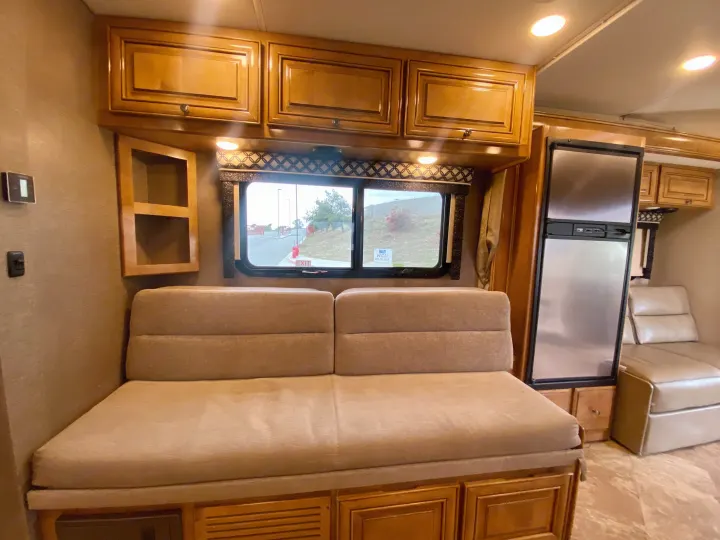 RV rental interior: comfy sofa, overhead cabinets, window view, & large refrigerator, offering a practical living space.. Thor Motor Coach Siesta 2017