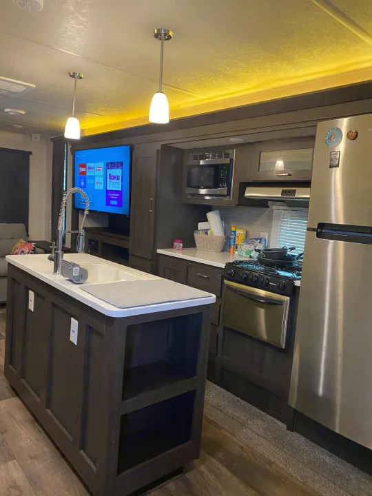 Inside a spacious RV rental: full kitchen with island, stainless steel appliances, and TV lounge area.. Forest River Wildwood 2018