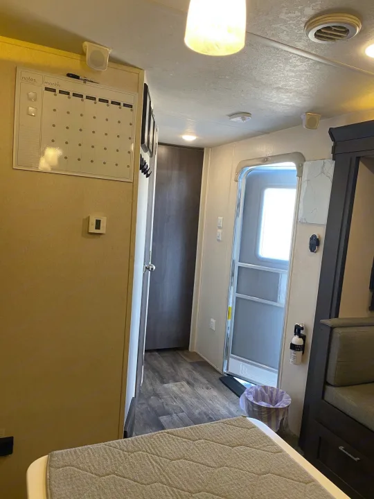 Cozy RV rental interior with calendar, thermostat, main door, and seating. Practical amenities like a fire extinguisher.. Forest River Wildwood 2018