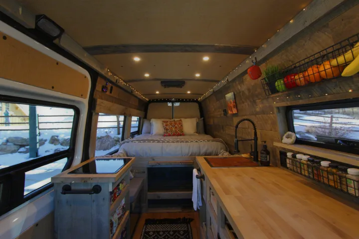 Cozy custom RV rental interior with a spacious bed, fully equipped kitchen, and warm lighting, perfect for van life adventures.. Mercedes-Benz Sprinter 419 LWB High Roof 2020