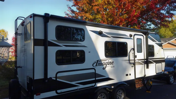 Grand Design Imagine XLS travel trailer, perfect for an RV rental. Parked outside with vibrant autumn trees in the background.. Grand Design Imagine XLS 2021