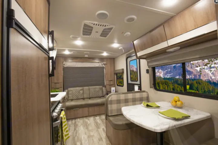 Cozy RV rental interior with dinette, sofa, kitchen, and scenic mountain views from windows.. Grand Design Imagine XLS 2021