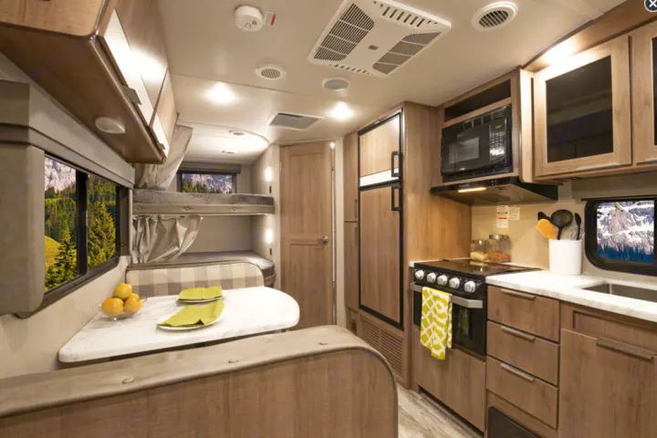 RV rental interior featuring a full kitchen, dining area, and bunk beds, perfect for comfortable travel.. Grand Design Imagine XLS 2021