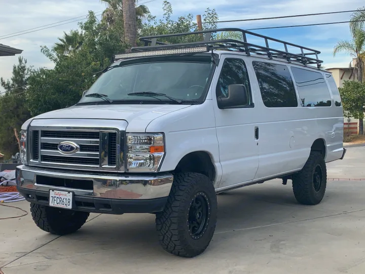 White lifted Ford van with roof rack & light bar, perfect for an RV rental adventure.. Ford Ford E350 2014