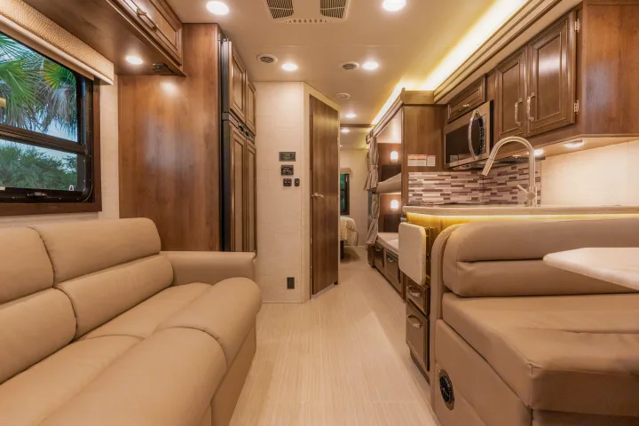 Spacious, modern RV rental interior featuring a living area with sofa, kitchen, dinette, and bunk beds. Perfect for travel.. Entegra Coach Esteem 31F 2021