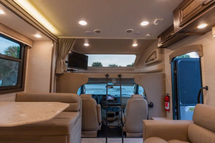 Spacious RV rental interior with comfortable living area, dining space, and accessible driver's cab, ideal for travel adventures.. Entegra Coach Esteem 31F 2021