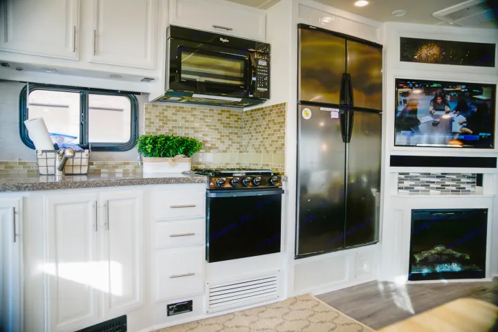 Explore this modern RV rental's full kitchen (sink, microwave, stove, fridge) & living area with TV & fireplace.. Fleetwood Bounder 2015