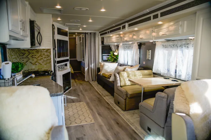 Bright, inviting RV rental interior: modern kitchen with backsplash, cozy living and dining areas.. Fleetwood Bounder 2015