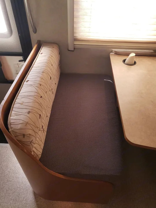 Cozy RV rental dinette with patterned back cushion, dark textured seat, and a light-colored table.. Fleetwood Pulse 2009