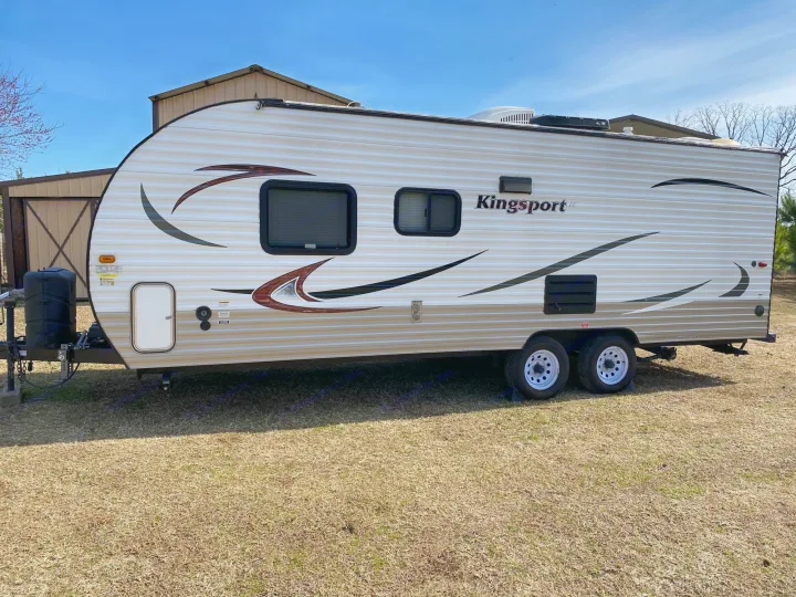 White Kingsport travel trailer (RV) parked on grass. Ideal for your next RV rental road trip!. Gulf Stream Kingsport 2015