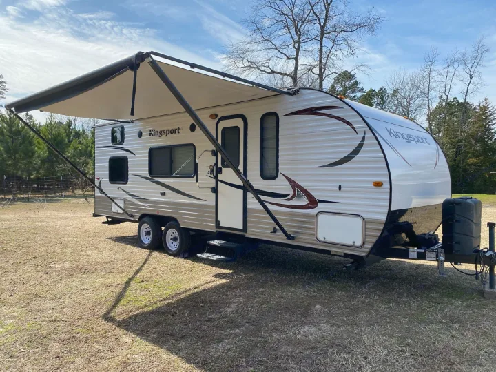 Bright, modern Kingsport travel trailer RV with extended awning on a sunny day. Ideal for your next outdoor rv rental getaway.. Gulf Stream Kingsport 2015