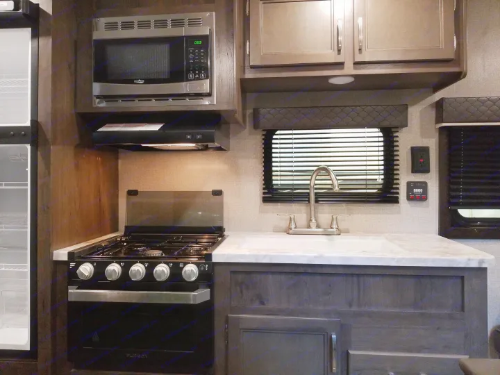 Modern RV rental kitchen interior: microwave, gas stove, sink, refrigerator, and storage. Perfect for your next mobile adventure.. Jayco Jay Flight 2021