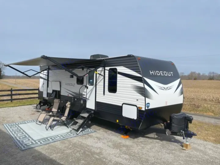 This spacious RV rental travel trailer with an extended awning and outdoor setup is ready for your next adventure.. Keystone Hideout 2021