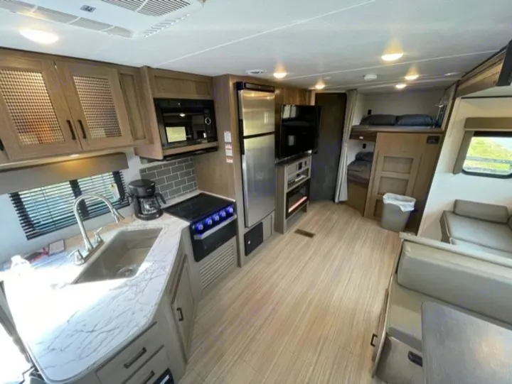 Modern RV rental interior showcasing a full kitchen, living space, and bunk beds.. Keystone Hideout 2021