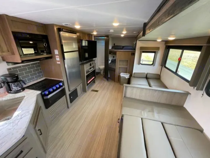 Modern RV rental interior showcasing a full kitchen, comfy living area, and rear bunks. Ready for adventure!. Keystone Hideout 2021