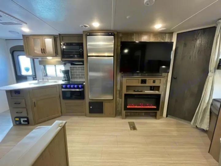 Spacious RV rental interior: kitchen with microwave/stove/fridge, living room with TV and electric fireplace.. Keystone Hideout 2021
