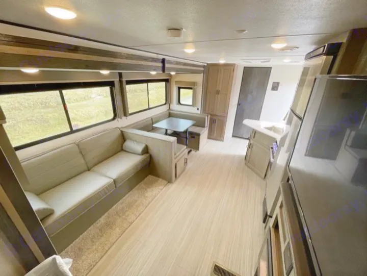 Modern RV rental interior: a spacious living area with sofa, dining booth, and full kitchen. Ideal for adventure.. Keystone Hideout 2021