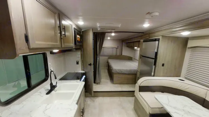 This rv rental showcases a modern, spacious interior with a full kitchen, comfortable bed, and dinette area, ideal for travel.. Coachmen Freelander 2022