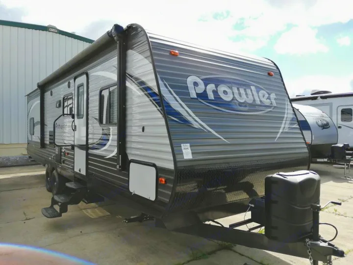 This Prowler travel trailer, a spacious option for rv rental, features a gray exterior, awning, and steps.. Heartland Prowler Lynx 2018