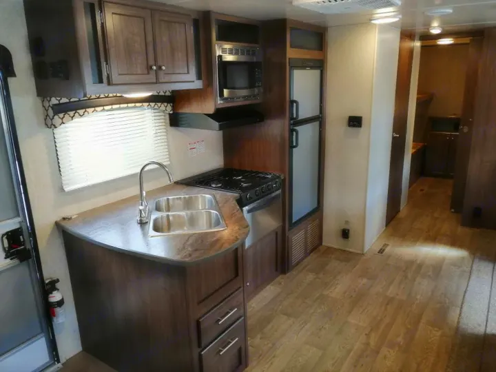 This modern RV rental features a full kitchen with a double sink, stove, and fridge, plus a cozy living space.. Heartland Prowler Lynx 2018
