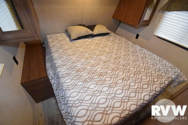 Cozy RV bedroom featuring a bed with patterned comforter and built-in storage. Ideal for your next rv rental trip.. Heartland Prowler Lynx 2018