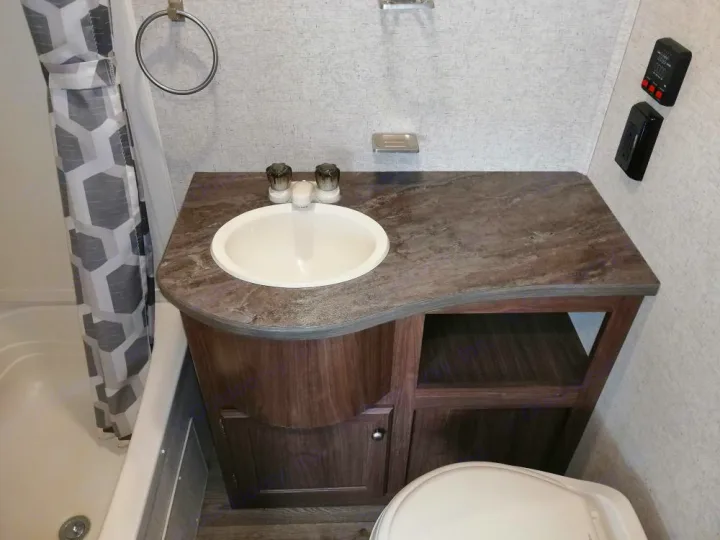 RV rental bathroom showing a compact vanity with sink, shower/tub, toilet, and wall-mounted controls.. Heartland Prowler Lynx 2018