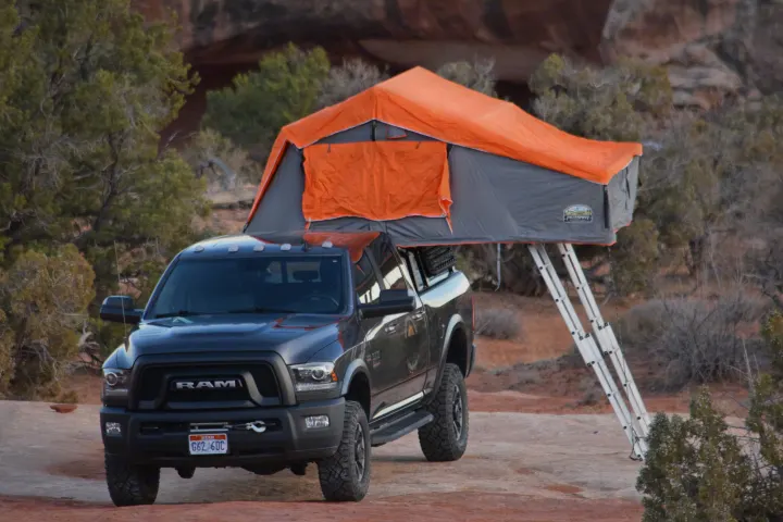 Rugged Ram pickup with orange rooftop tent and ladder, deployed for an RV rental outdoor adventure.. RAM Power Wagon 2018