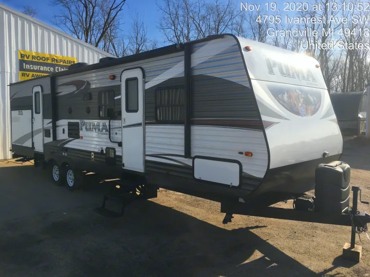 White & grey Puma travel trailer, an ideal RV rental for camping adventures. Parked at a service facility.. Palomino Puma 2016