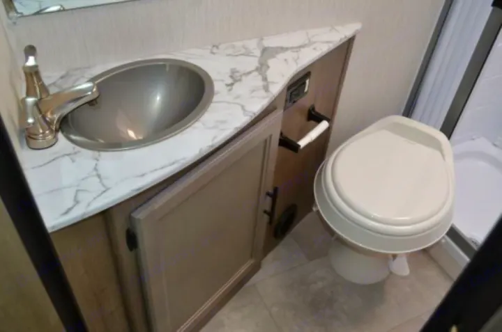 RV rental bathroom featuring a modern sink, marble-look counter, and toilet. Compact design for travel comfort.. Coachmen Freelander 2022