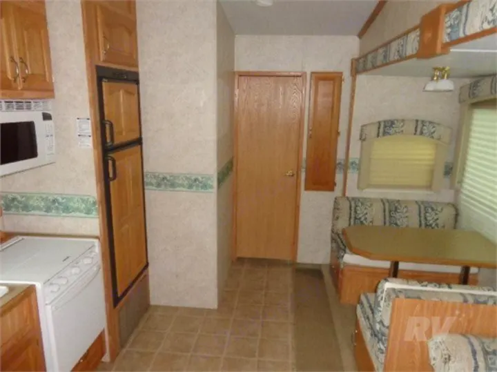 RV rental interior: kitchen with microwave, stove, fridge, and a dining booth. Features light wood cabinetry and functional design.. Other Other 2005