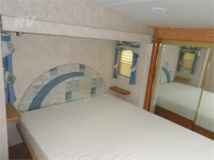 Cozy RV rental bedroom with a comfy bed, small shelves, windows, and mirrored closet. Ideal for travel!. Other Other 2005