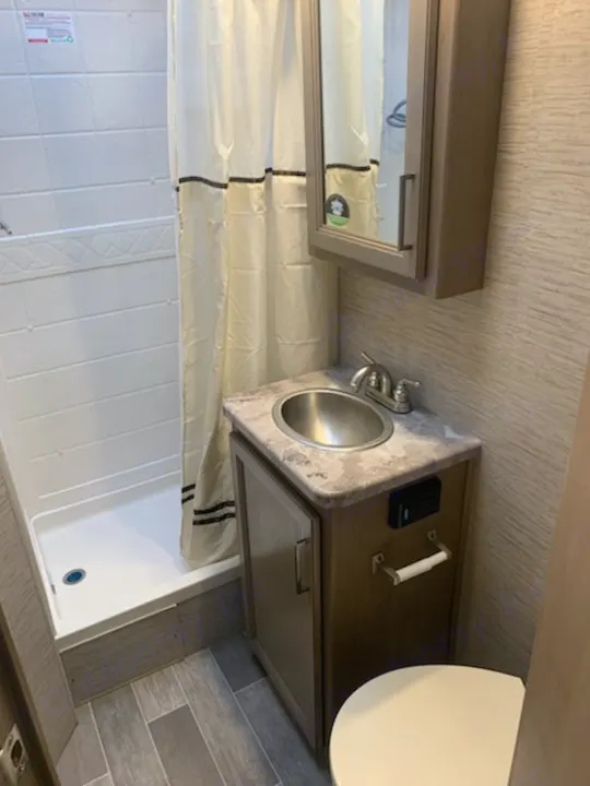 Private bathroom with shower, sink, and toilet, medicine cabinet, locked door. Thor Motor Coach Chateau 2021