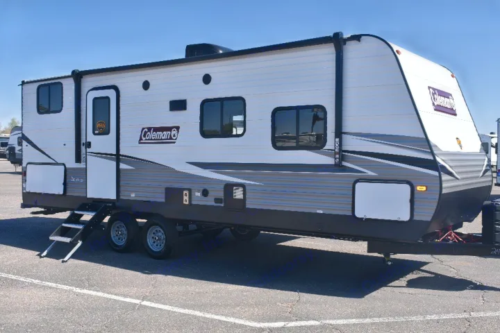A modern white and gray Coleman travel trailer with graphic decals, parked outdoors, ideal for an RV rental.. Dutchmen Coleman 2021