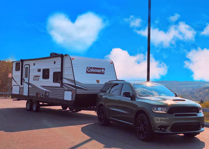 Ready for an RV rental adventure! Green SUV towing a Coleman travel trailer under a heart-shaped cloud.. Dutchmen Coleman 2021