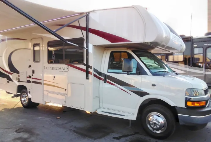 A white Coachmen Leprechaun Class C RV rental, featuring an extended awning. Ready for your next motorhome adventure.. Coachmen Leprechaun 2020