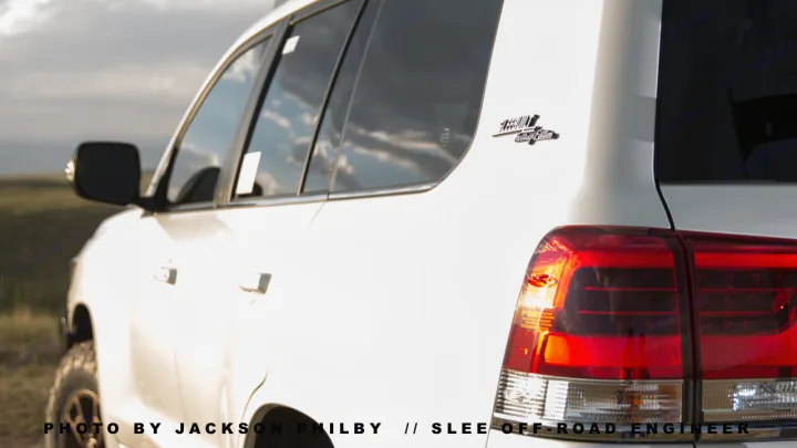 White Slee-built off-road SUV, rear passenger side view, with large red tail lights. Ideal for adventures where an rv rental won't fit.. Toyota Land Cruiser 200 Series 2021