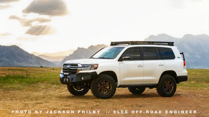White off-road SUV parked in a vast mountain landscape, offering a robust alternative to an RV rental for wilderness adventures.. Toyota Land Cruiser 200 Series 2021