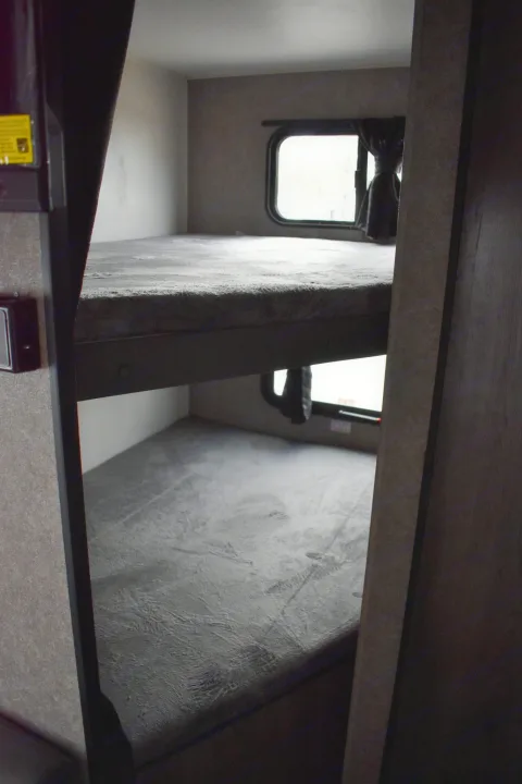 Cozy bunk beds in an RV rental, perfect for family adventures. Each bunk has a window for natural light and views.. Open Range 20MB 2021
