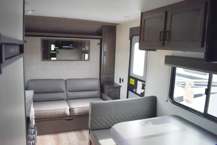 Spacious RV rental interior with a modern gray sofa, dining area, and ample storage, offering comfort for travel adventures.. Open Range 20MB 2021