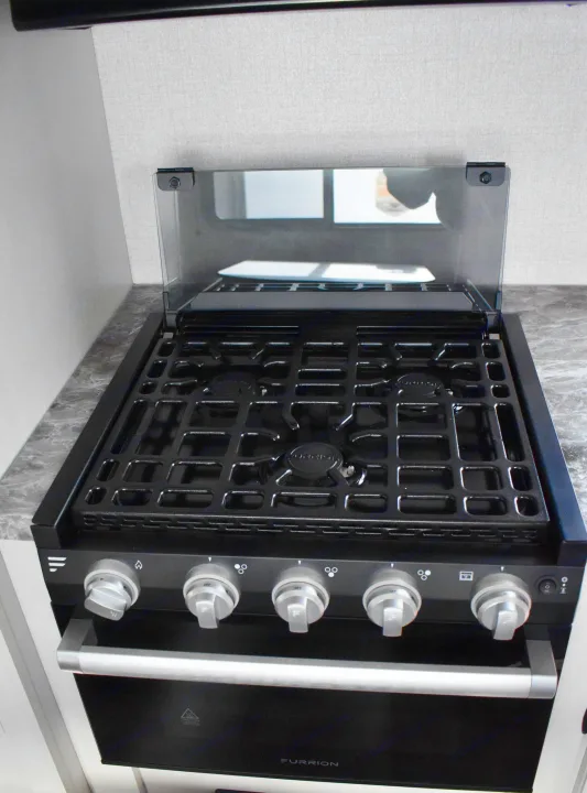 RV rental kitchen: A black Furrion gas stove and oven with an open glass cover. Essential for travel cooking.. Open Range 20MB 2021
